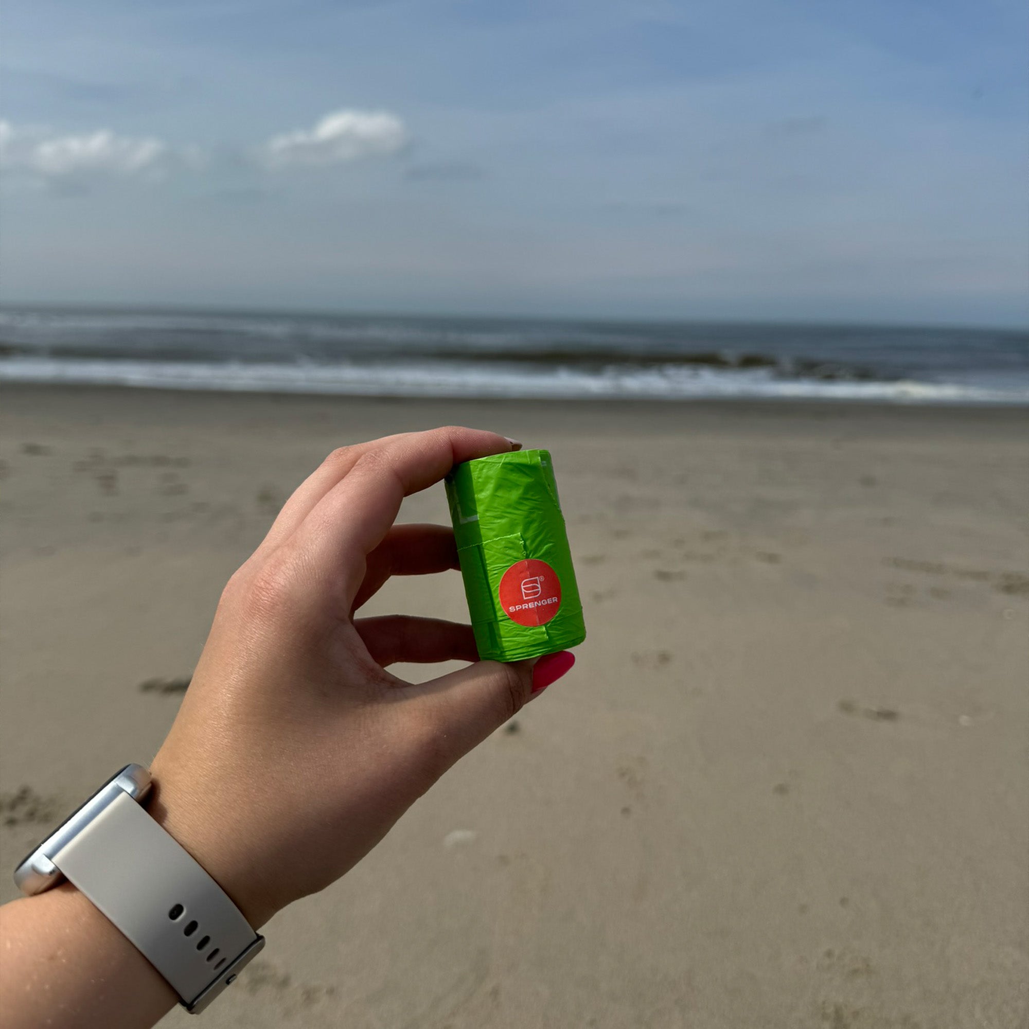 Hundekotbeutelrolle in der Hand am Strand