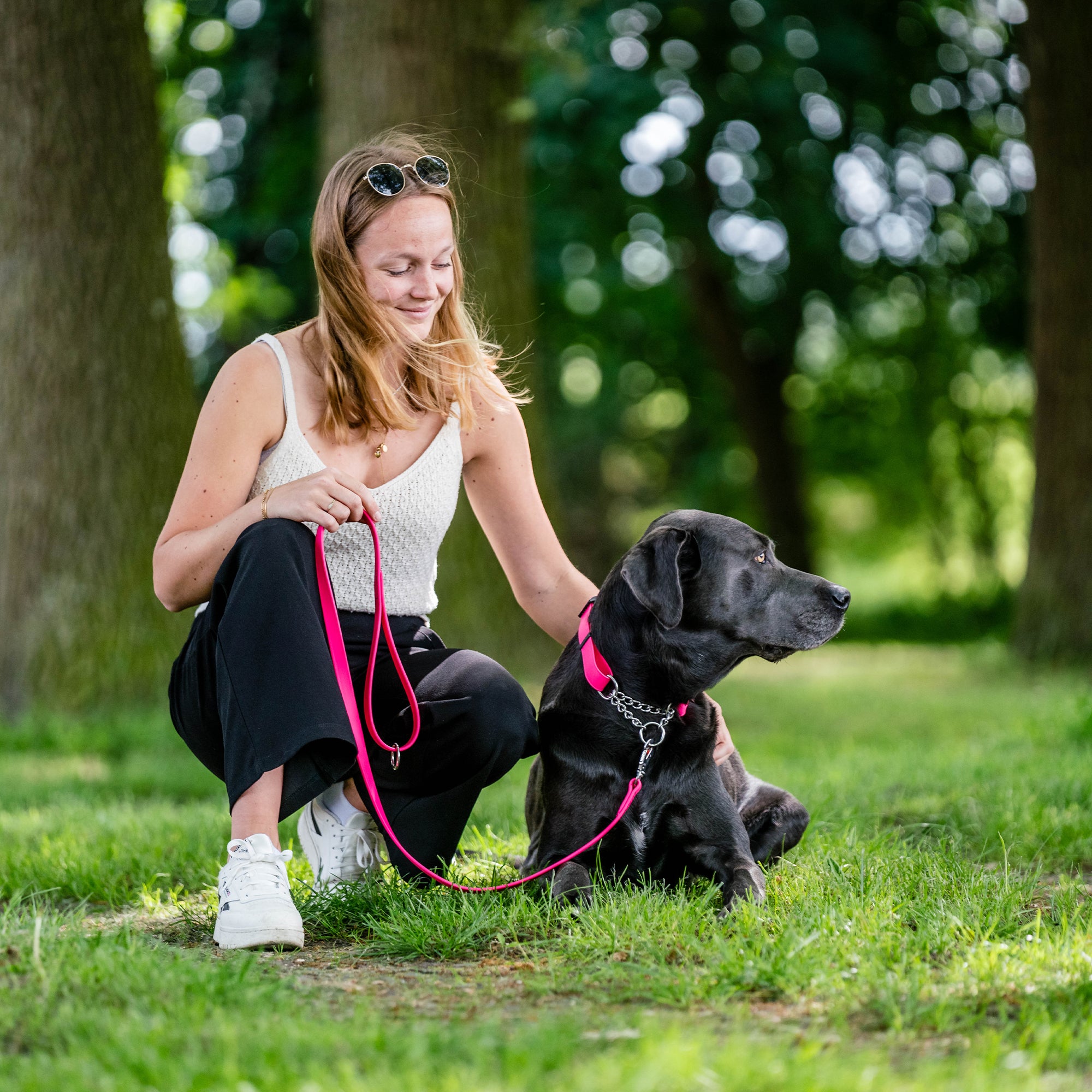 Frau und schwarzer Hund mit pinken Biothane Halsband und pinker Biothane Hundeleine im Wald